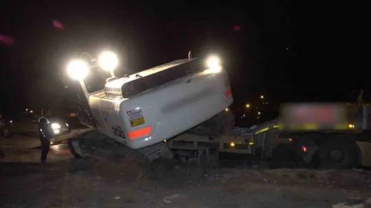 Deprem bölgesine giden tırın taşıdığı iş makinesi yola devrildi