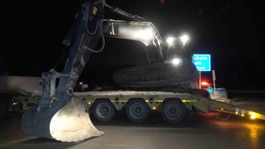 Deprem bölgesine giden tırın taşıdığı iş makinesi yola devrildi